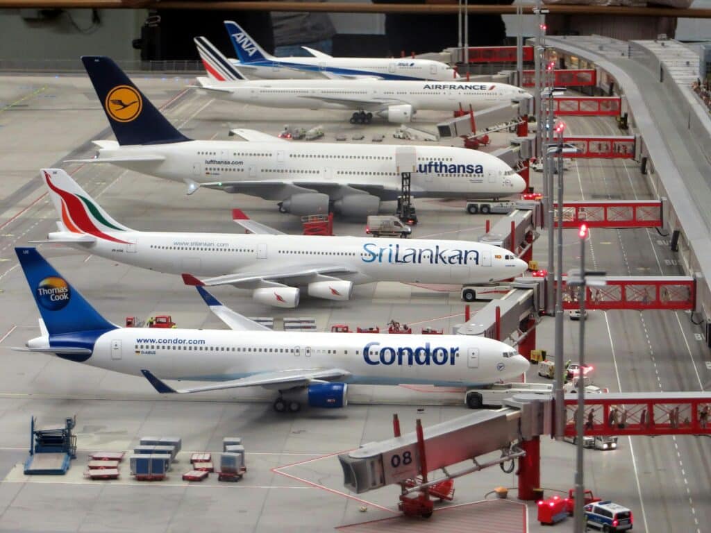 Five different international flights including a Condor and Sri Lankan air flight docked for passengers at an airport. 