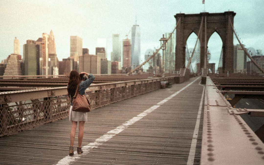 Woman taking photo of Brooklyn Birdge on trip to New York City after securing a US entry waiver