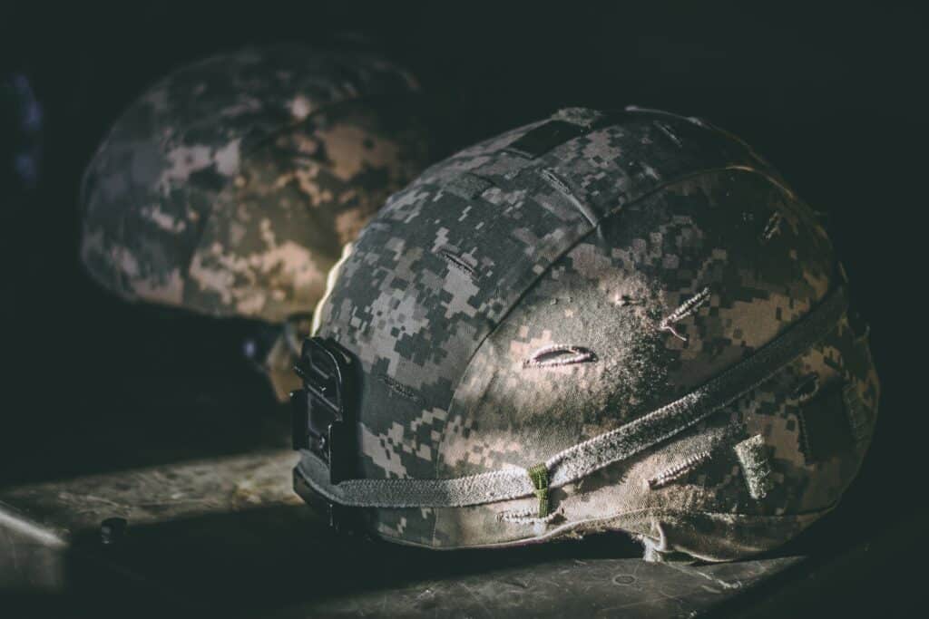 Army helmets resting on a shelf in a dark room
